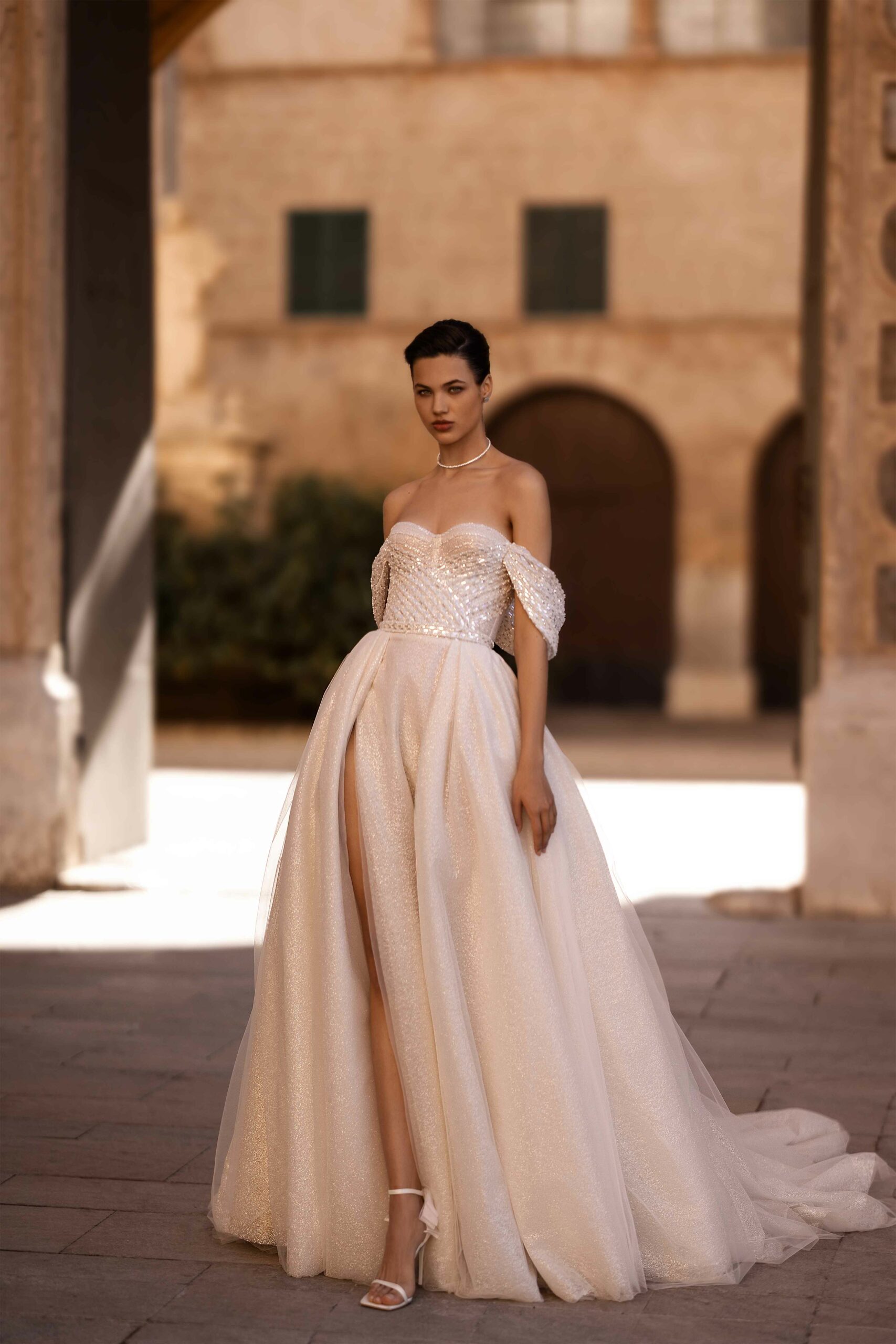 Abito da sposa Peony Wonà con corpetto brillante, spalle scese, ampia gonna luminosa con spacco frontale e lunga coda, disponibile presso Altomare Sposa a Modena.
