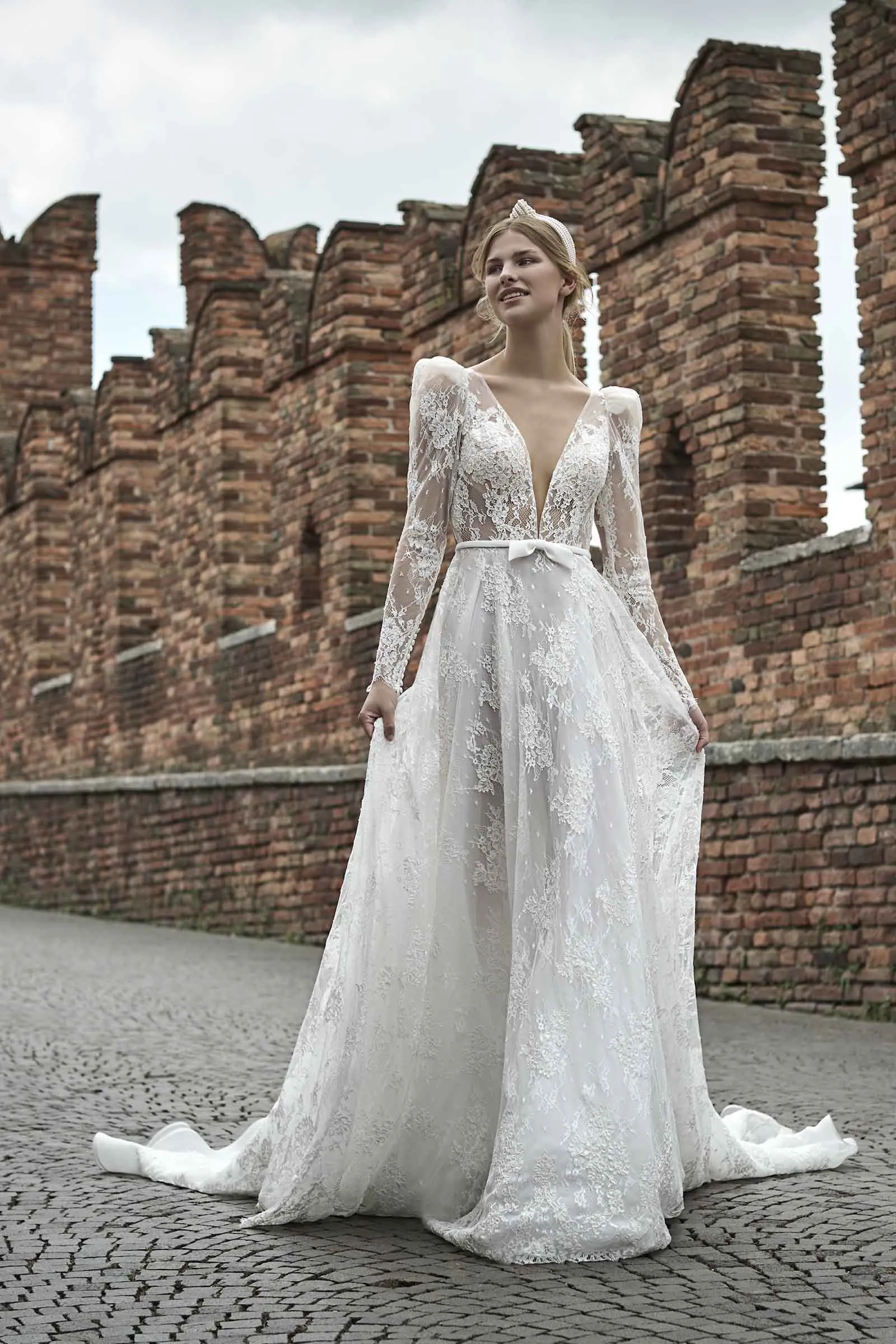Anemone di Maison Signore conquista con pizzo floreale, scollo profondo e maniche lunghe leggere, abbinati a una gonna ampia e romantica. Un modello raffinato per spose eleganti, disponibile da Altomare Sposa a Modena.