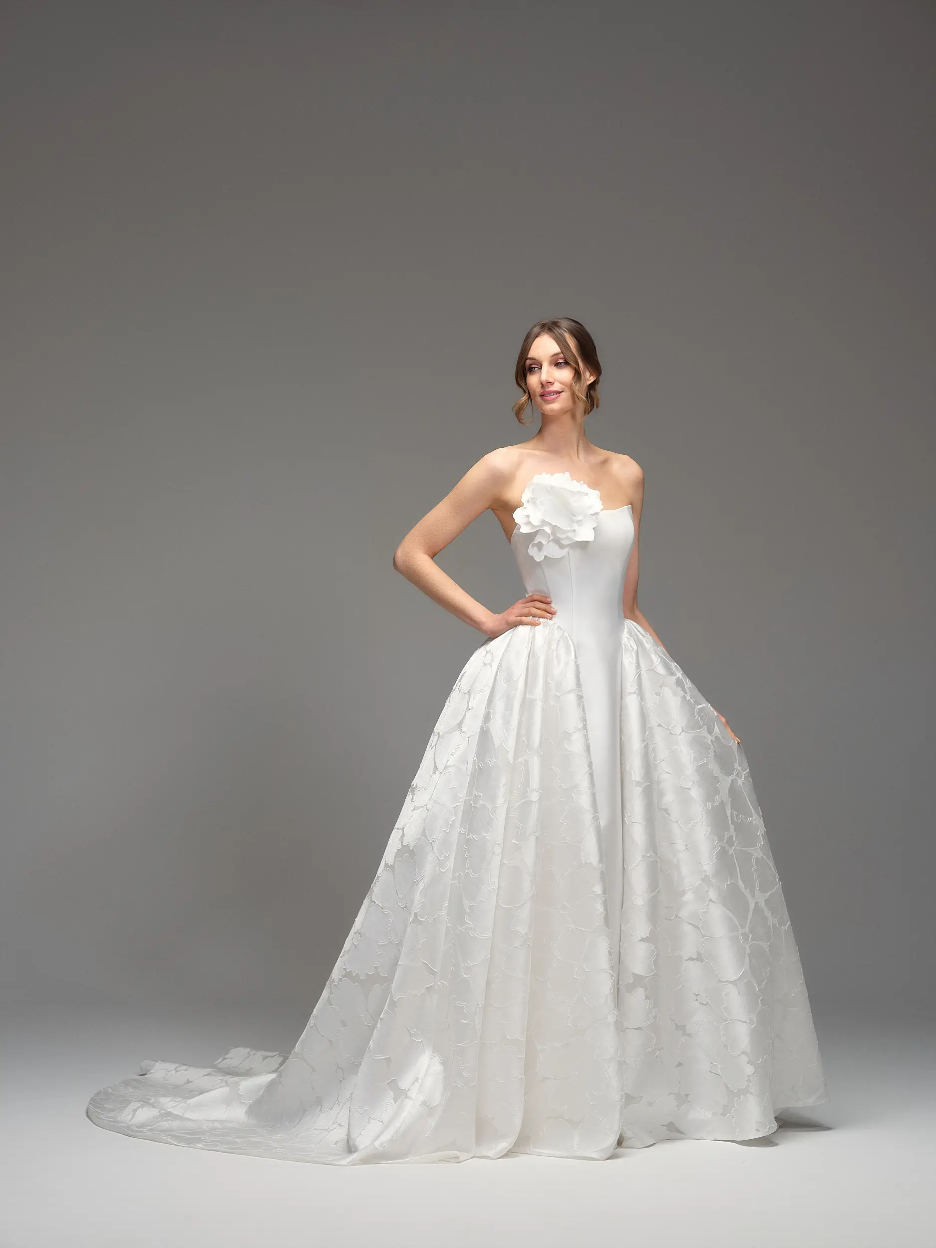 Abito da sposa Ilenia di Maria Pia con scollo dritto, maxi fiore applicato sul bustier e ampia gonna jacquard con strascico, fotografato in studio su sfondo neutro, disponibile da Altomare Sposa a Modena.