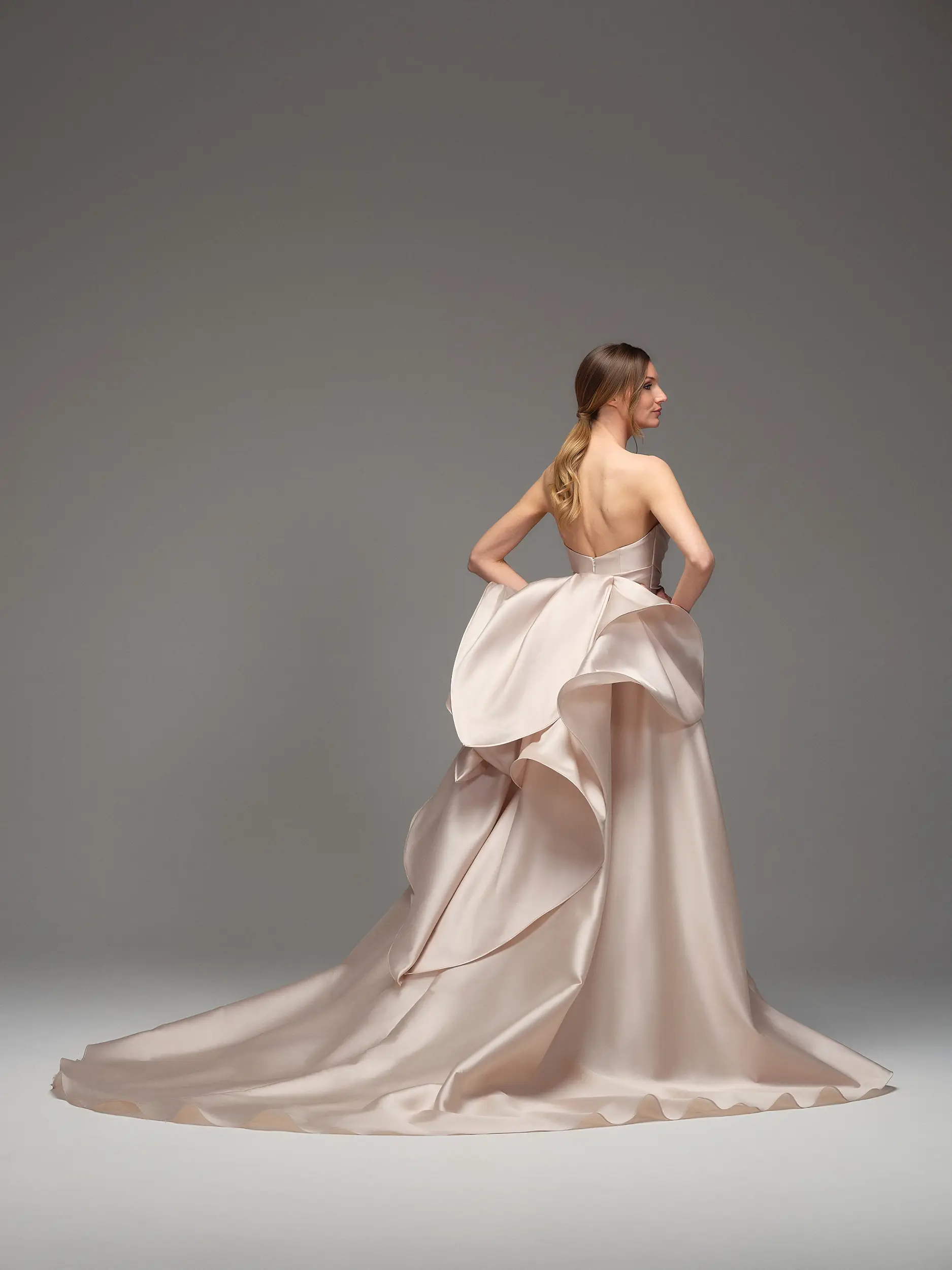 Retro dell’abito Maria Pia Isbel con schiena scoperta, maxi volant strutturato e lunga coda satinata cipria, disponibile da Altomare Sposa atelier a Modena.