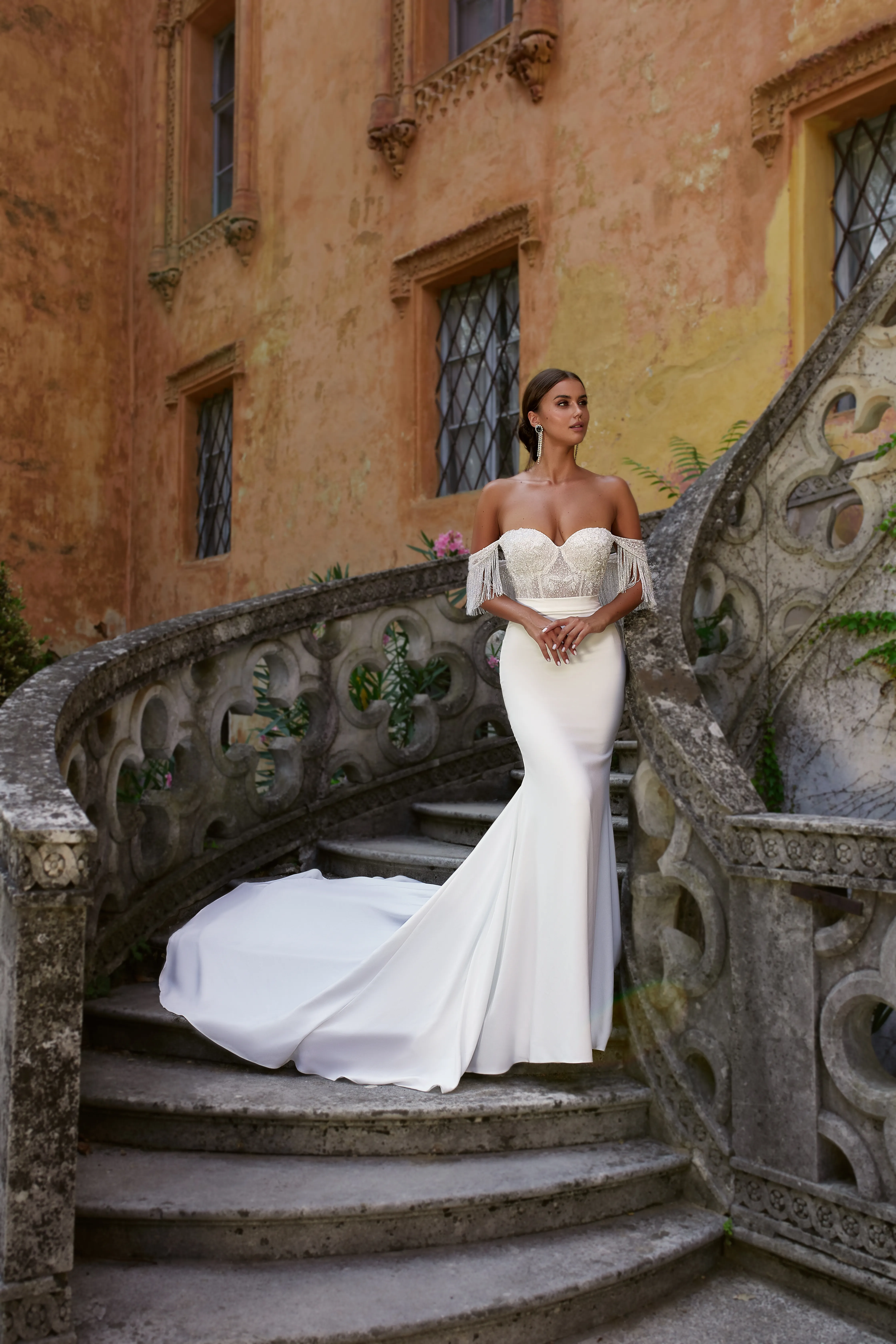 Abito da sposa Margarita di Maison Signore a sirena con corpino brillante, spalle scese con frange gioiello e gonna liscia con lungo strascico, fotografato su una scenografica scalinata in pietra di villa storica.
