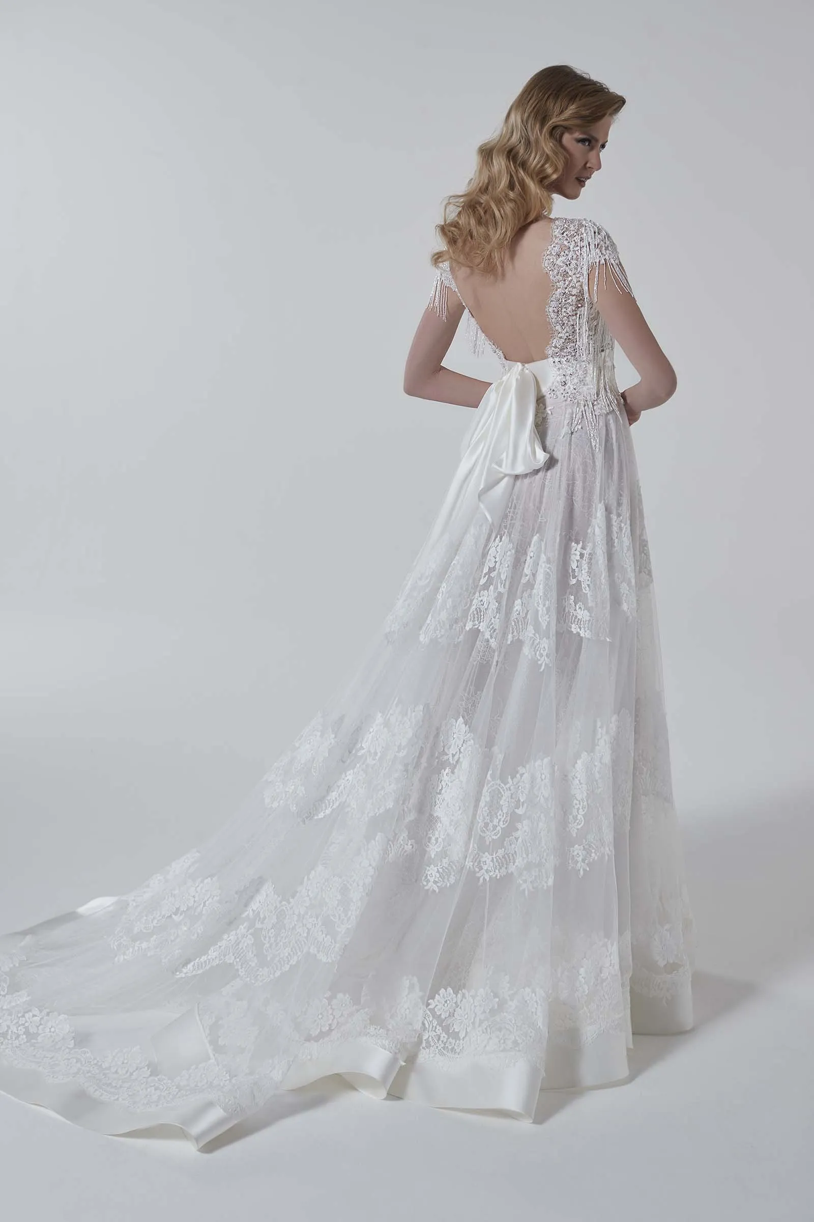 Abito da sposa Renata di Maison Signore con schiena scoperta, dettagli ricamati sulle spalle, fiocco posteriore, ampia gonna in tulle con pizzo e lungo strascico, disponibile da Altomare Sposa a Modena.
