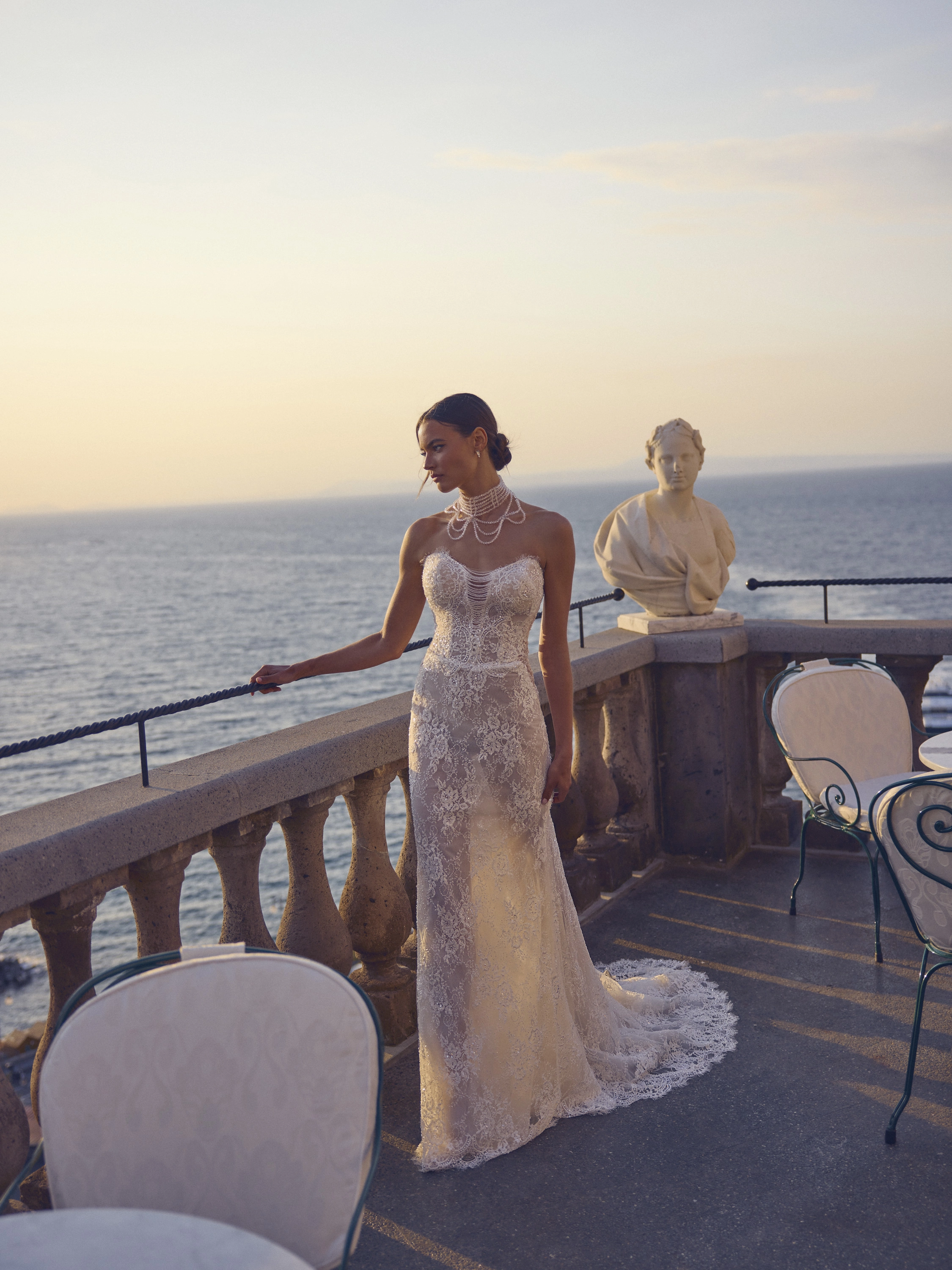 Abito da sposa Vivienne in pizzo aderente con strascico, indossato su terrazza vista mare, Altomare Sposa atelier Modena
